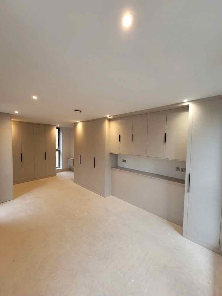 Floor-to-ceiling fitted wardrobes with high-level cupboards in a stone colour finish