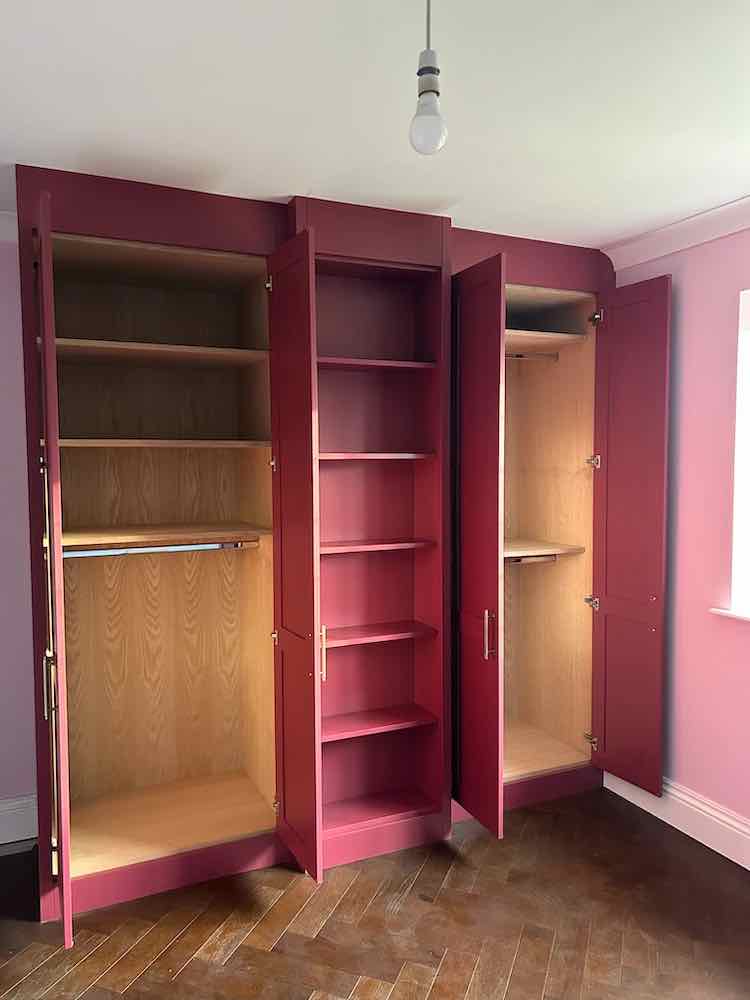 Two painted wardrobes either side of a central open shelving unit