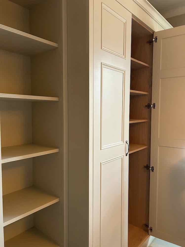 Painted shaker-style wardrobe door open showing oak-veneer shelving inside